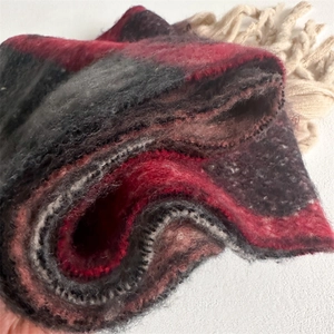 Close-up of thick winter scarf with multi-color block patterns and long white tassels