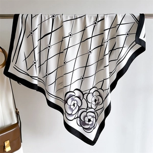 Macro detail of silk texture square scarf featuring black diamond lattice and camellia floral print