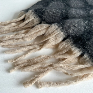 Macro detail of thick faux cashmere scarf featuring grey knit texture and beige tassels