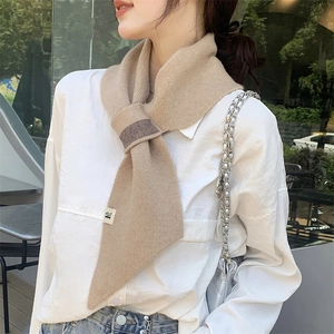 Detailed close-up of a camel knitted scarf with dark brown loop and brand tag detail