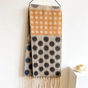 Detail of soft thick scarf with vibrant polka dot pattern and long tassel edges