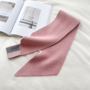Close-up of pink knitted scarf with grey trim, soft cashmere texture and logo tag
