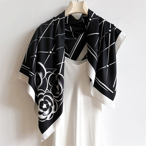 Detailed view of silk square scarf featuring camellia prints and geometric grid patterns
