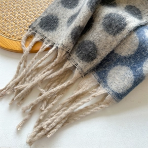 Close-up of knit scarf texture with large colorful dots and fringe tassels decoration