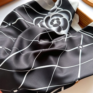 Macro detail of diamond grid silk scarf with camellia motif in a rustic basket
