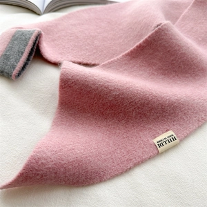 Close-up of pink knitted scarf showing soft fiber texture and dark grey color block