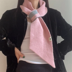 Detail of pink knitted scarf with grey trim featuring a cross-over slit and 'H' tag