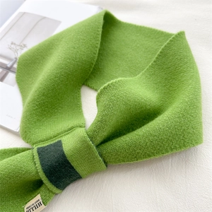 Detail of cross-knot knitted scarf in grass green with soft ribbed texture and warm loop