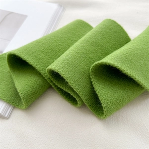 Detail of green knitted scarf showing soft wool texture and fine stitching craft