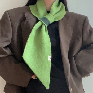Close-up of bright green knitted neckerchief with dark grey loop detail on brown blazer