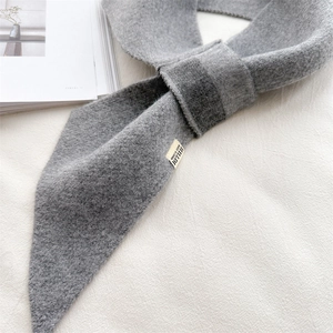 Close-up of thick grey knitted scarf with soft texture and brand label detail