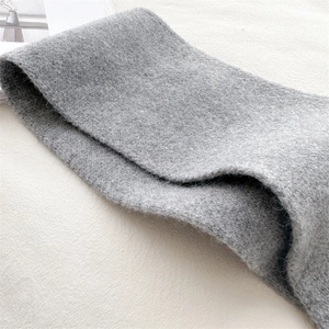 Close-up of grey knitted scarf showing soft fleece texture and detailed fabric craftsmanship