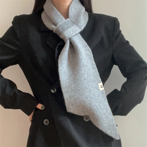 Detail of grey knitted scarf showing soft texture and cross-through loop styling