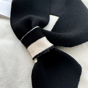 Close-up of thick knitted scarf showing black and white contrast weaving and soft texture