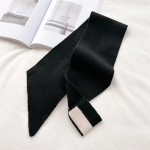 Detailed knit texture of a minimalist black scarf with white block accent on white fabric