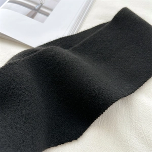 Close-up of soft black knitted wool scarf fabric showing rich textured detail and warmth