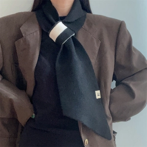 Detail of minimalist black knitted scarf with contrast white loop fastening and texture