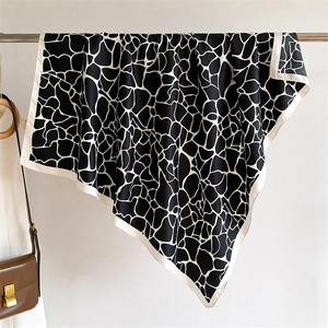 Détail du foulard en soie imprimé girafe montrant la texture bicolore et le beau drapé
