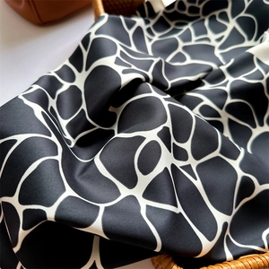 Détail du foulard en soie à motif girafe noir et blanc montrant la texture satinée lisse