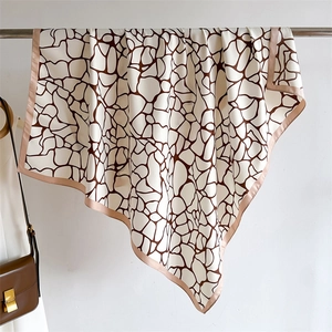 Détail d'un grand foulard en soie à motifs géométriques marron style girafe moderne