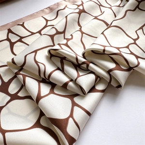 Vue détaillée d'un foulard en soie crème avec motifs géométriques marron et bords