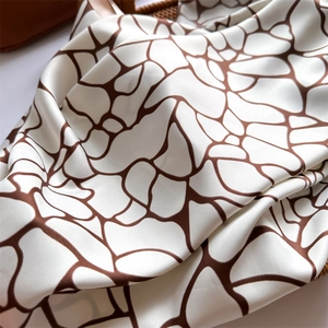 Gros plan d'un foulard en soie à motifs géométriques marron dans un panier tressé