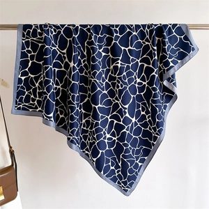 Détail du foulard en soie montrant l'imprimé girafe abstrait et le drapé lisse du tissu