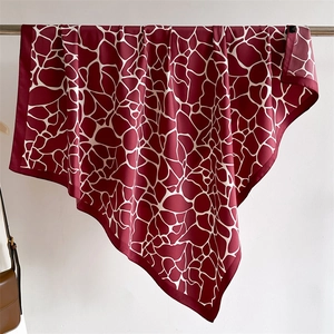 Détail d'un foulard carré en soie bordeaux avec motifs géométriques blancs et fini lustré