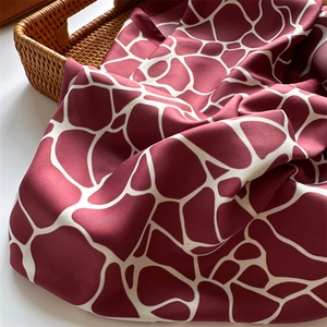 Détail d'un foulard en soie géométrique marron et blanc drapé sur un panier tressé