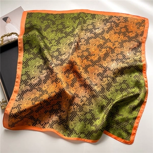 Detailed view of paisley silk scarf featuring orange borders and green gradient patterns
