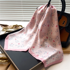 Pink satin square scarf with paisley and heart patterns draped over a luxury handbag