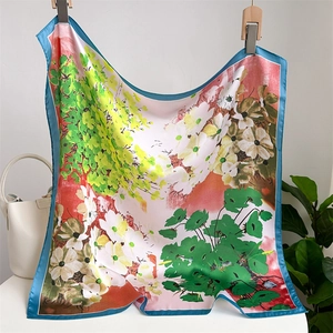 Floral print square silk scarf with blue border displayed with a white handbag