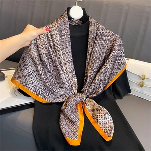 Elegant tan and beige weave silk scarf with vibrant orange borders on black backdrop