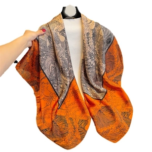 Elegant large orange silk scarf featuring sophisticated feather patterns and luxury drape