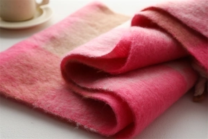 Détail d'une écharpe à carreaux rose et beige montrant une texture douce style cachemire