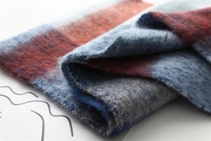 Détail de l'écharpe douce à carreaux bleus et gris montrant la texture épaisse et frangée