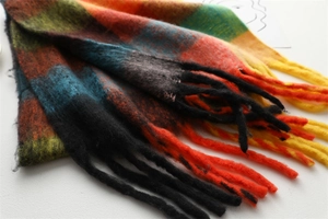Gros plan détaillé de l'écharpe en maille à carreaux avec couleurs vives et franges