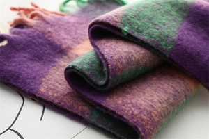 Détail d'une écharpe épaisse à carreaux violets et verts avec des franges douces