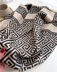 Détail d'un foulard en soie montrant une texture mate et un motif grec noir sur beige