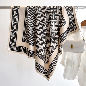 Détail du foulard en soie montrant le motif de méandre grec élégant et la texture lisse