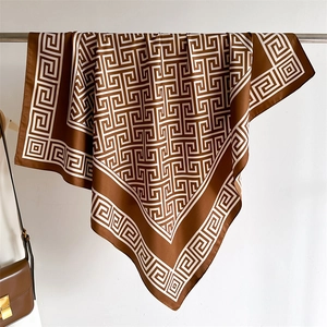 Détail d'un carré de soie marron chocolat avec motif grec géométrique sur un cintre