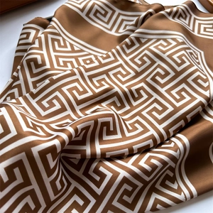 Détail d'un foulard en soie marron caramel aux motifs géométriques grecs de méandres