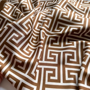 Détail d'un foulard carré en satin avec des motifs grecs marron et blanc et texture soyeuse