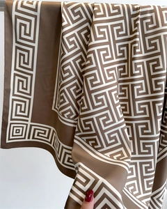 Gros plan d'un foulard en satin soyeux avec des motifs géométriques grecs marron et blanc