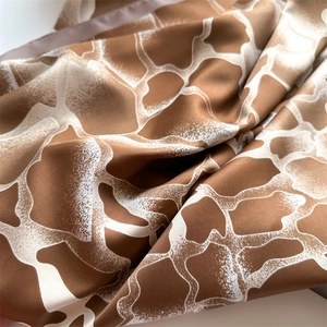 Vue détaillée de l'écharpe en satin au motif girafe marron et blanc, texture soyeuse