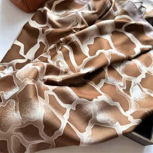 Détail d'un élégant foulard en soie sergé avec imprimé girafe marron et texture satin