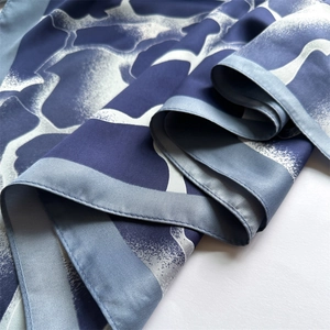 Détail macro d'un foulard en soie avec imprimé marbré bleu et texture satinée lisse