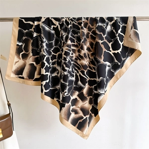 Détail d'un grand foulard carré en soie avec imprimé girafe et bordure beige suspendu avec élégance