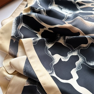 Détail d'un foulard en soie montrant une texture satinée et des motifs animaux dorés