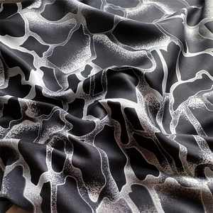 Détail de foulard en soie imprimé montrant des motifs abstraits noirs et blancs